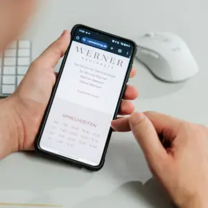 Frau hält Smartphone in der Hand mit der Website von Dres. Werner