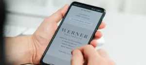 Frau hält Smartphone in der Hand mit der Website von Dres. Werner