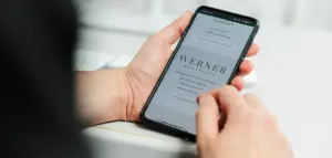 Frau hält Smartphone in der Hand mit der Website von Dres. Werner