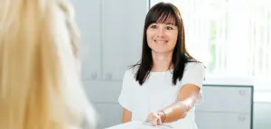 Patientin übergibt ausgefüllten Anamnesebogen